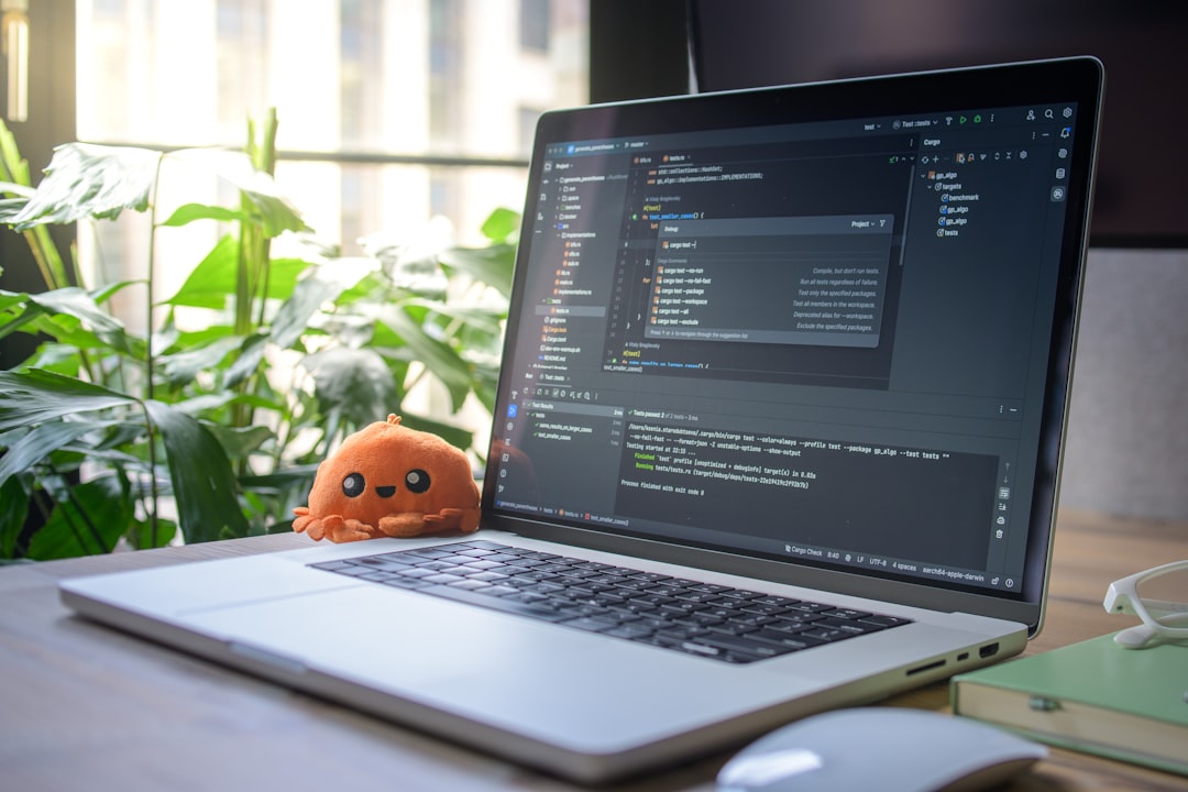Laptop displaying code with a small plush toy.