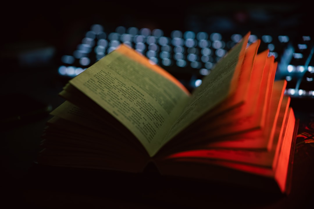 An open book sitting next to a computer keyboard
