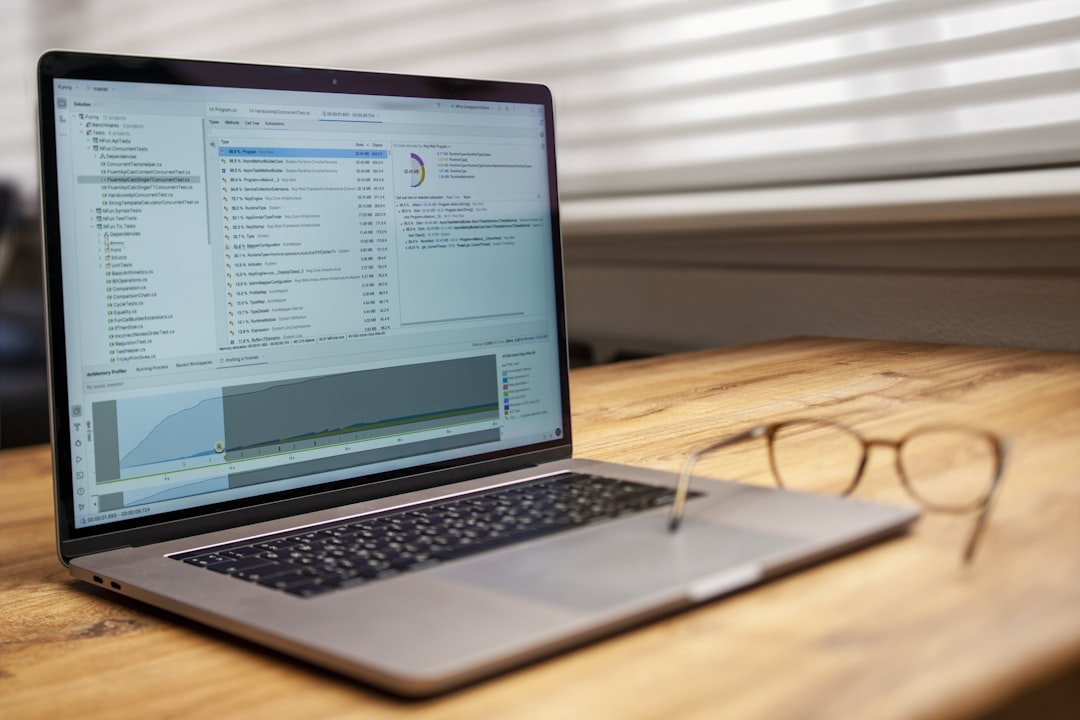 Laptop and glasses on a wooden desk.